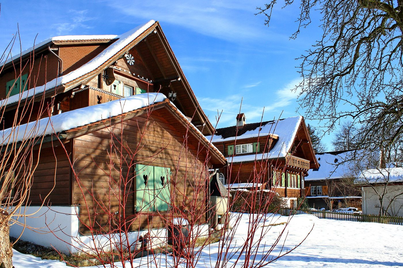 Snow-covered wooden chalets under a clear blue winter sky