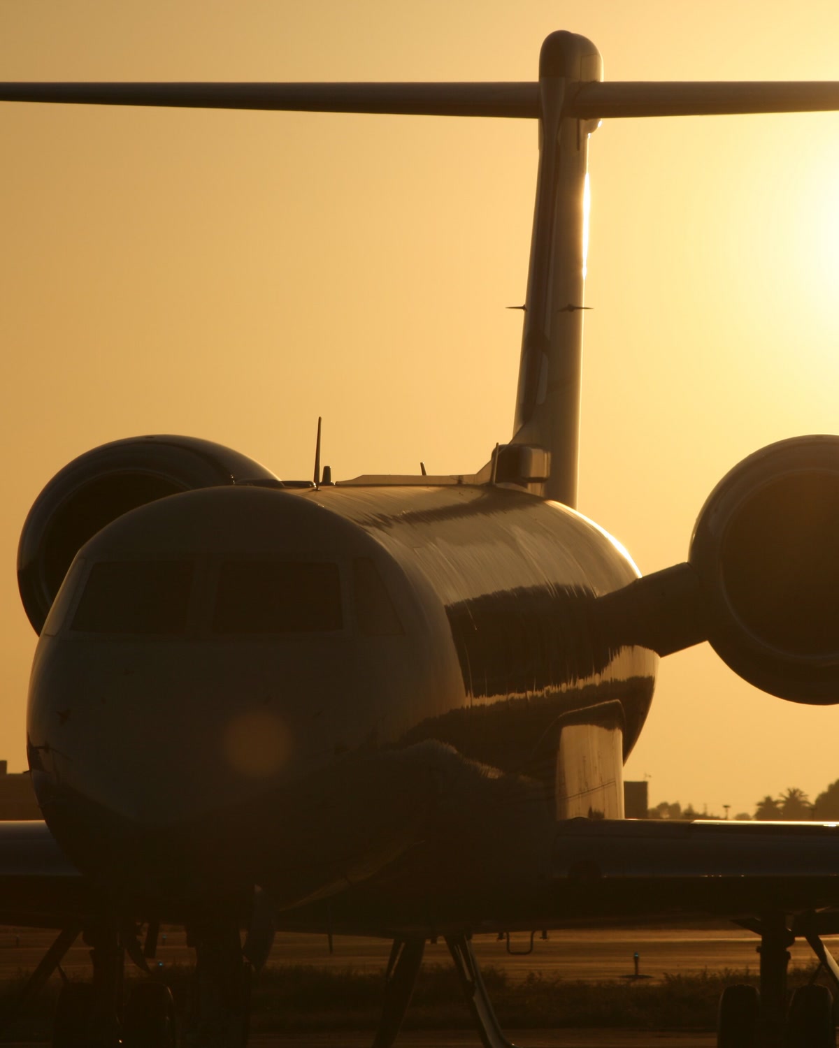 A private jet on the tarmac in silhouette against a golden sunset
