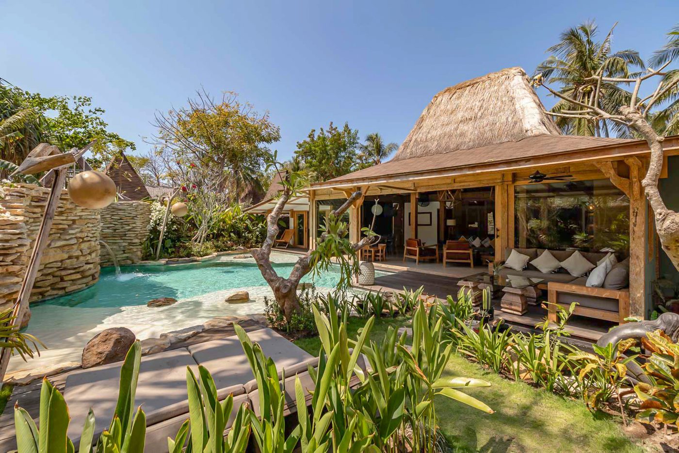 A private tropical villa with its own pool, daybeds and a thatched open-air lounge