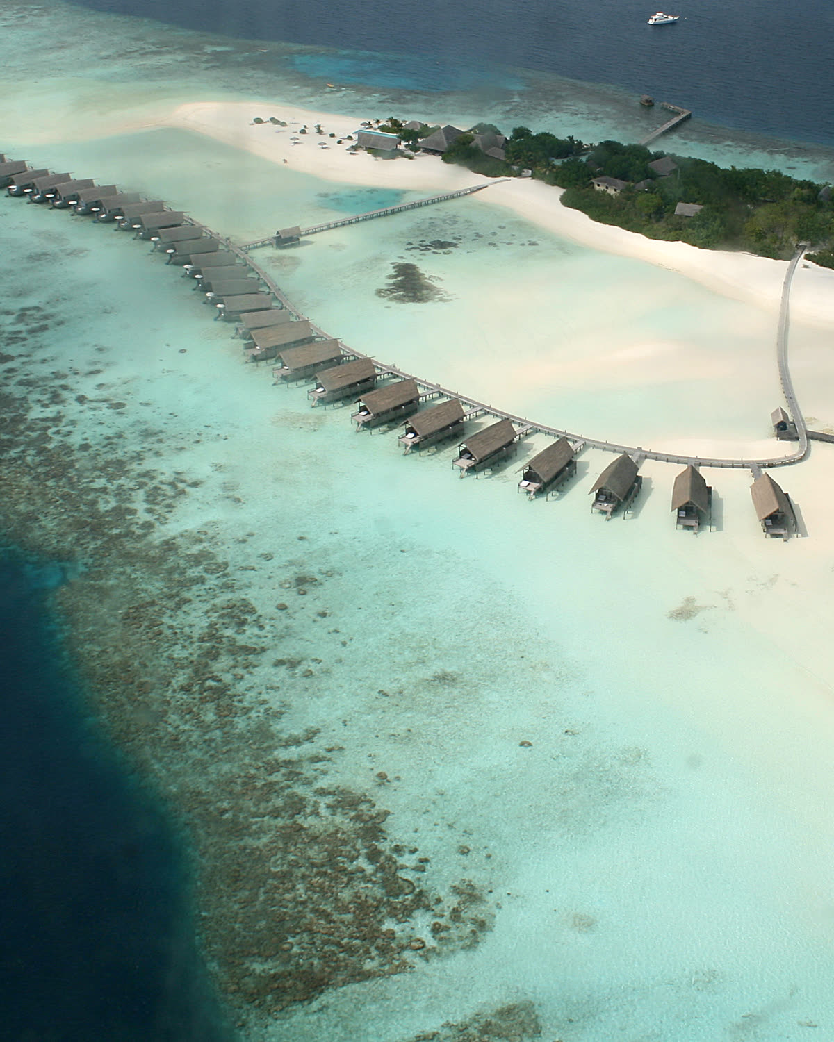 Overwater villas along a turquoise reef in the Maldives